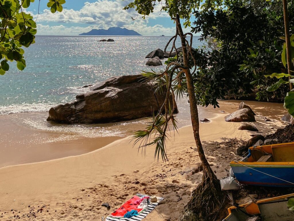 Sunset Beach auf Mahé, Seychellen, mit Blick auf das Meer und die vorgelagerte Insel Silhouette
