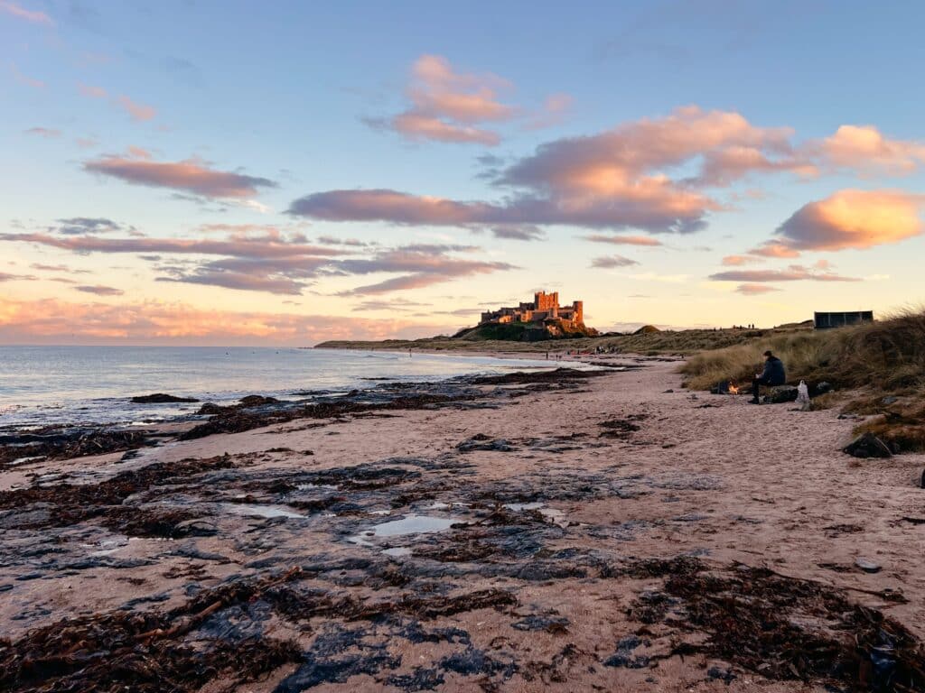 Bamburgh Castle am Strand von Bamburgh bei Sonnenuntergang in Nordengland, England