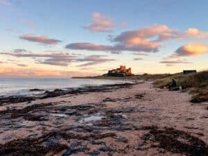 Bamburgh Castle am Strand von Bamburgh bei Sonnenuntergang in Nordengland, England