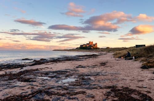 Bamburgh Castle am Strand von Bamburgh bei Sonnenuntergang in Nordengland, England
