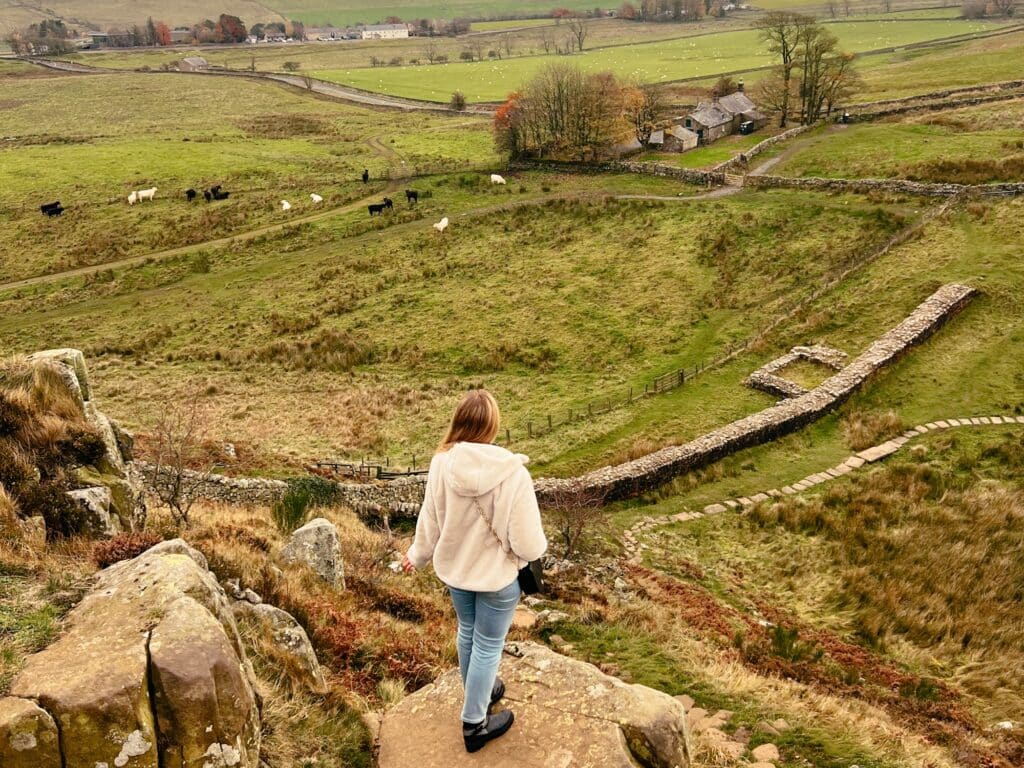 Wanderin am Hadrianswall in Northumberland während einer Nordengland Rundreise, die Richtung Sonnenuntergang blickt