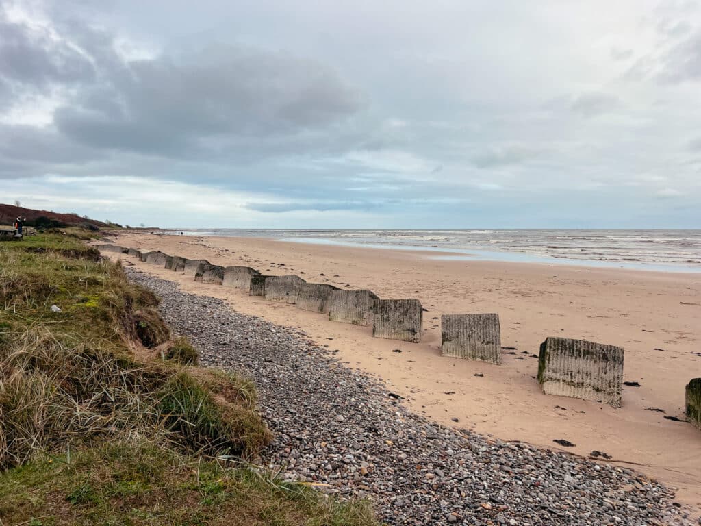 Weitläufiger Strand von Alnmouth in Northumberland mit Dünen, Sand und Betonblöcken am Ufer
