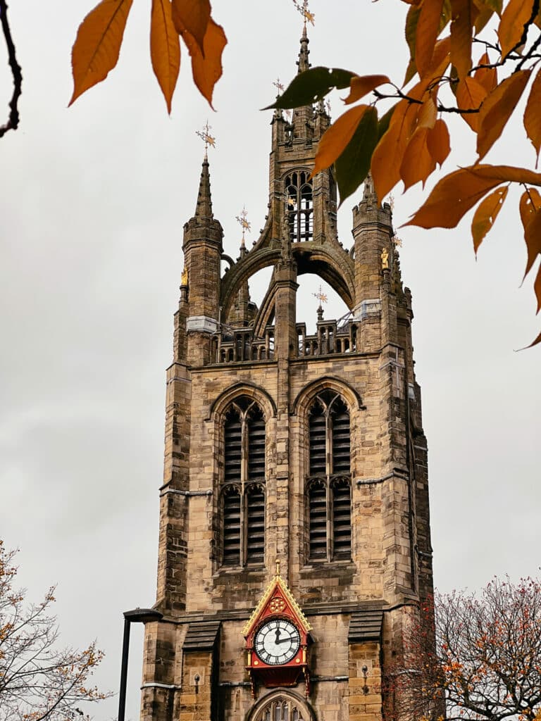 Außenansicht des Turms der St. Nicholas Cathedral in Newcastle upon Tyne mit herbstlichen Blättern im Vordergrund
