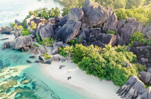 Anse Source d’Argent auf La Digue, einer der berühmtesten Seychellen Sehenswürdigkeiten, früh am Morgen kurz nach Sonnenaufgang mit leeren Stränden, Granitfelsen und türkisblauem Meer
