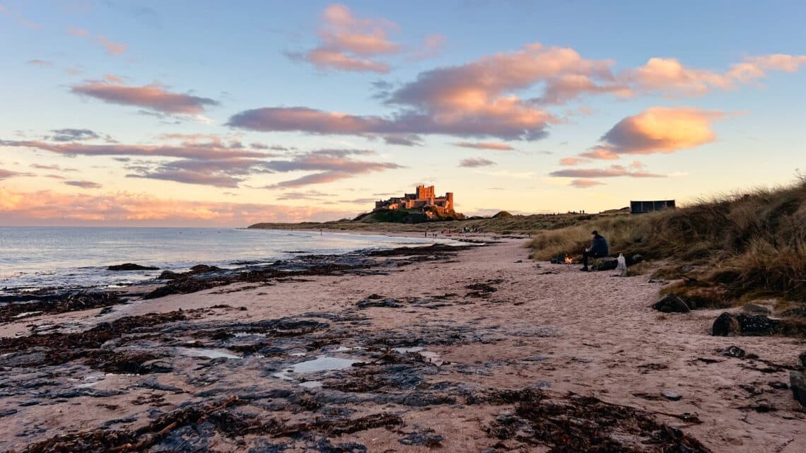 Bamburgh Castle am Strand von Bamburgh bei Sonnenuntergang in Nordengland, England