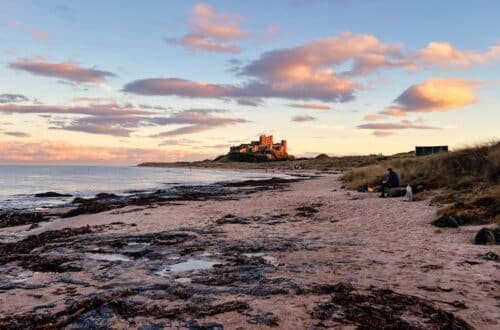 Bamburgh Castle am Strand von Bamburgh bei Sonnenuntergang in Nordengland, England